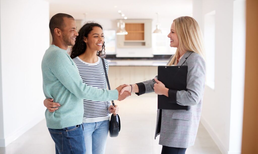 Real estate agent shaking hands with a happy couple building client relationship