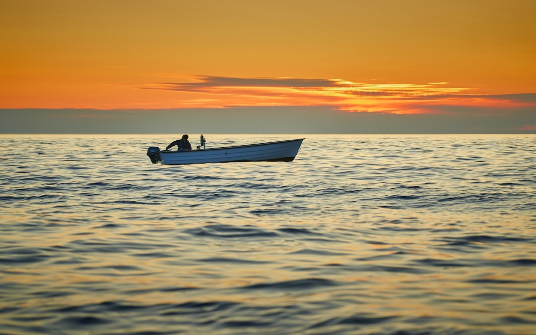 Professional deep sea fishing boat on the open ocean with the sun rising on the horizon, symbolizing a new day of opportun...