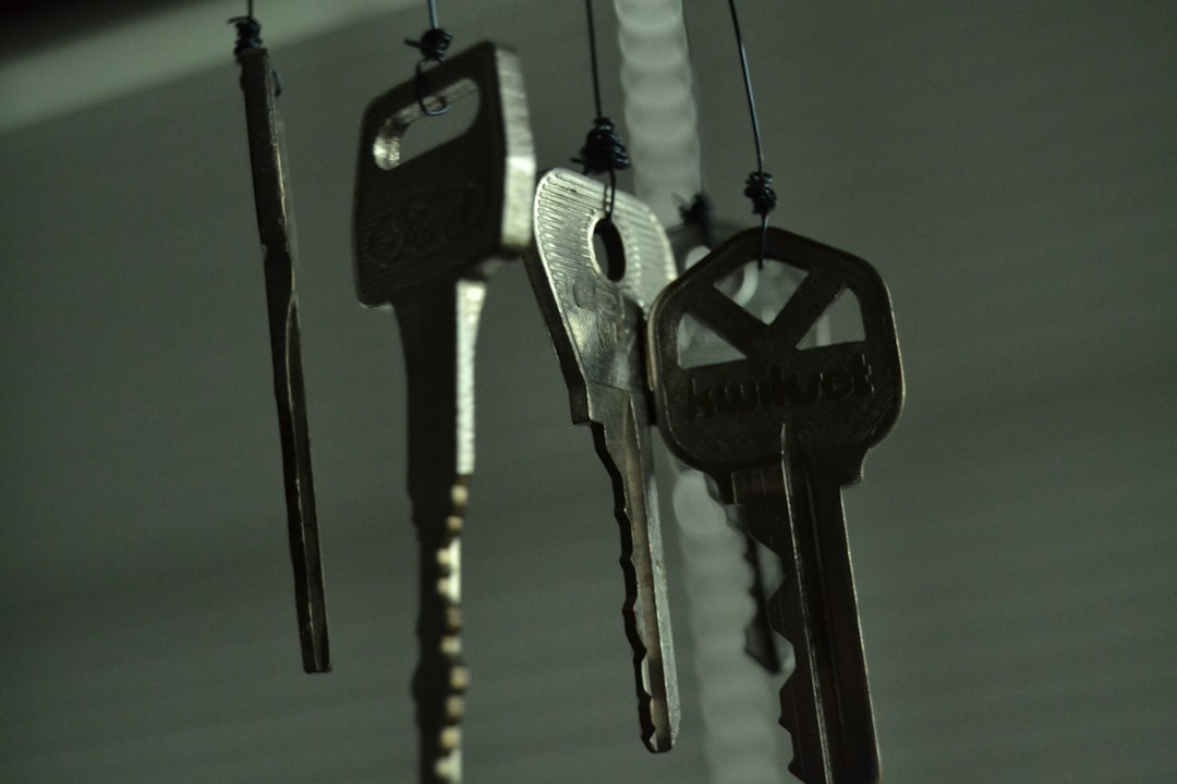 A close-up of a real estate agent's hand giving a set of house keys to a new homeowner in front of the blurred background of a beautiful, modern home.