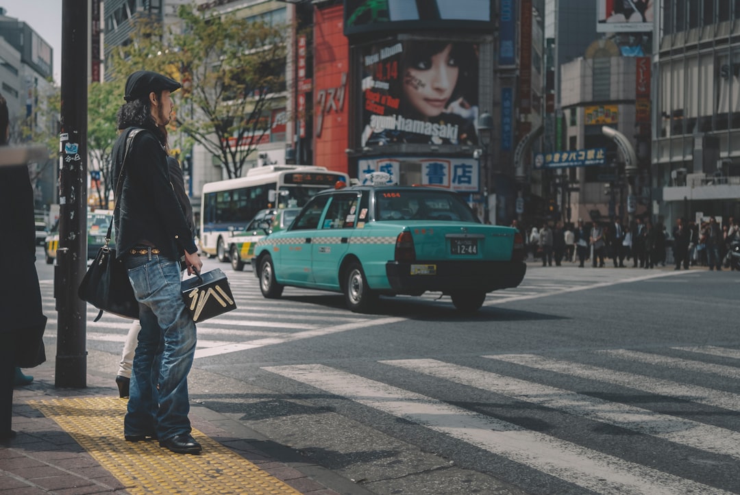 Person stands on a city street, looking at a map on their smartphone with a frustrated or confused expression, representin...