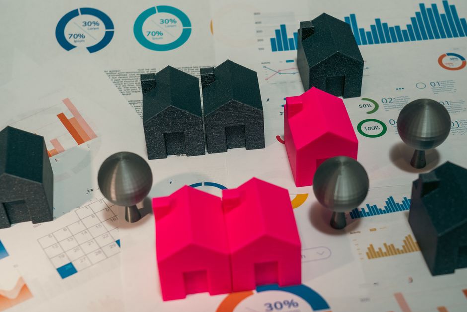 A clean, minimalist tabletop displays several distinct architectural models of homes, symbolizing the process of comparing different real estate franchise models.