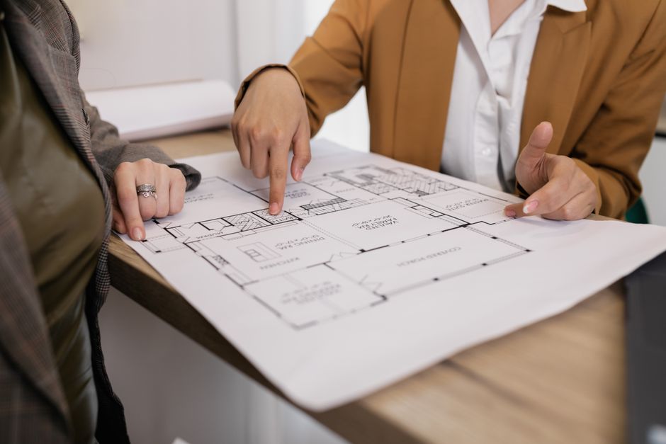 A professional real estate agent or homeowner carefully reviewing architectural blueprints on a clean, modern desk, symbolizing strategic home sale planning.