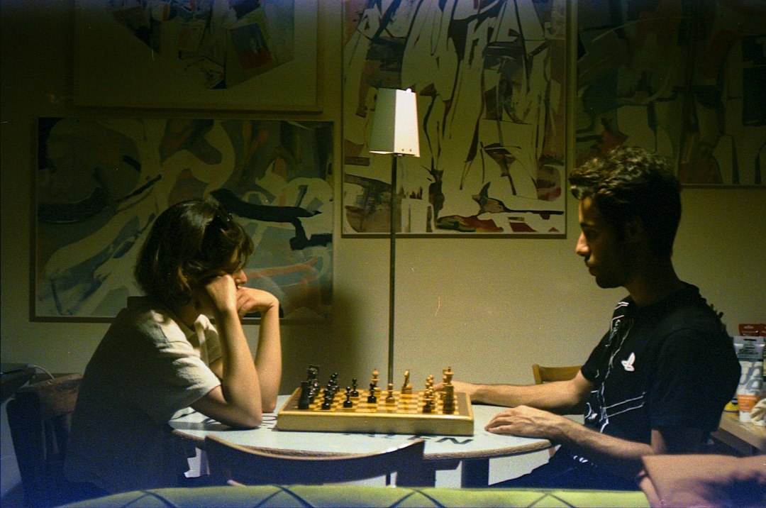 Close-up of a hand making a strategic move with a chess piece on a board, symbolizing the planning and vision of a busines...