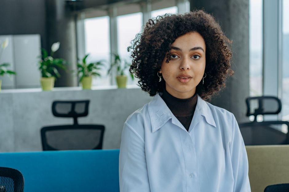 A professionally dressed person stands confidently in a bright, minimalist office, embodying the authority and ownership mindset of a business leader.
